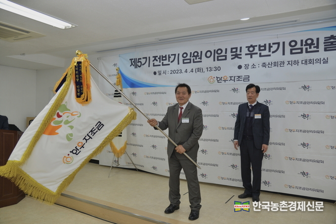 4일 서초구에 위치한 제1축산회관에서 진행된 ‘한우자조금 제5기 전·후반기 임원 이임 및 출범식’ 행사에서 이동활 신임 한우자조금 관리위원장(왼쪽)이 민경천 전임 위원장(오른쪽)으로부터 자조금기를 전수 받은 후 깃발을 흔들고 있다. kenews.co.kr